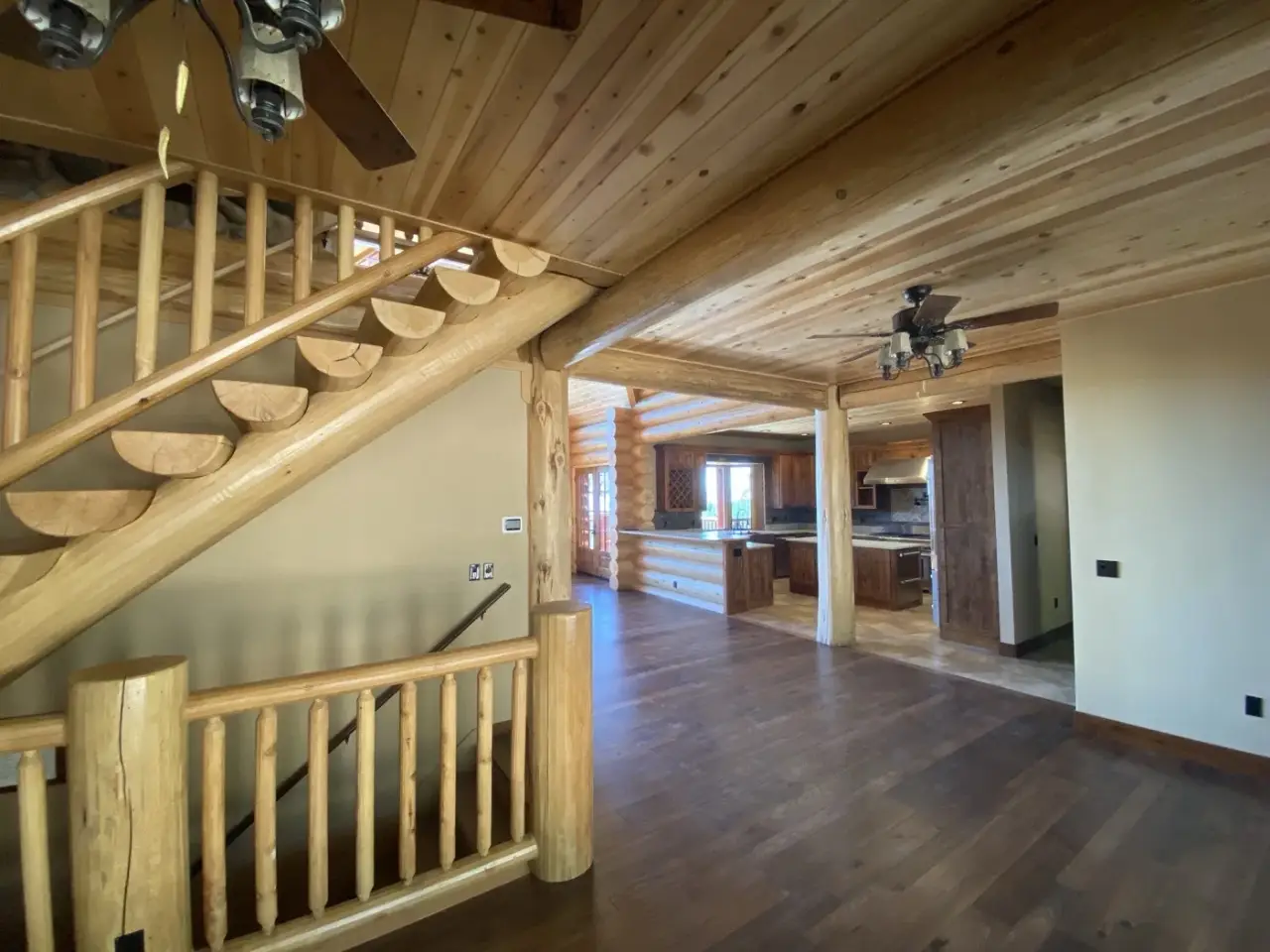 Inside a finished log home: a log staircase under a wood ceiling.
