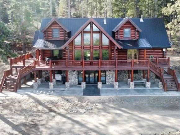 A finished log lodge with a glass prow front and full width deck.