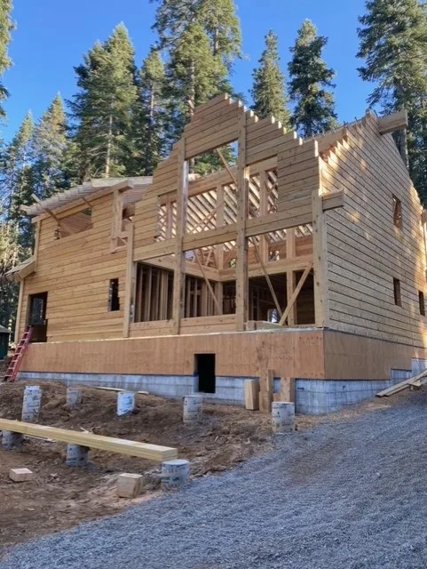 A two story log shell with the gable end framed open to the sky.