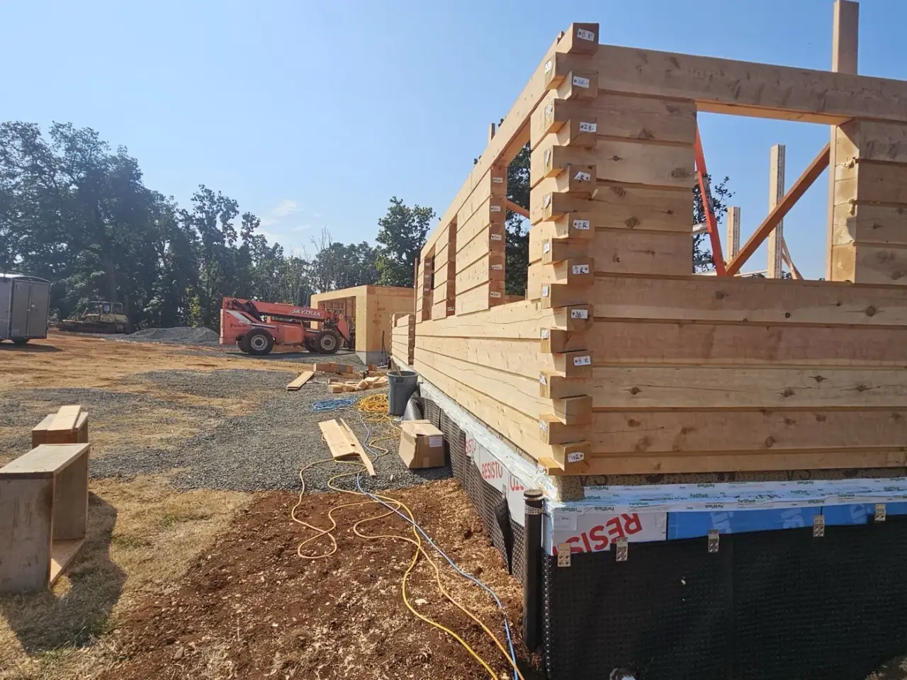 Milled log walls rising at a corner, each course numbered on its end.